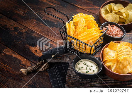 Mix of Crinkle Potato chips served with dip sauce and sea salt. Wooden background. Top view. Copy space Mix of Crinkle Potato chips served with dip sauce and sea salt. Wooden background. Top view. Copy space 101070747