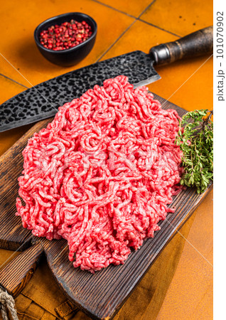 Fresh Raw Mince, Ground beef and pork meat on a butcher board. Orange background. Top view 101070902