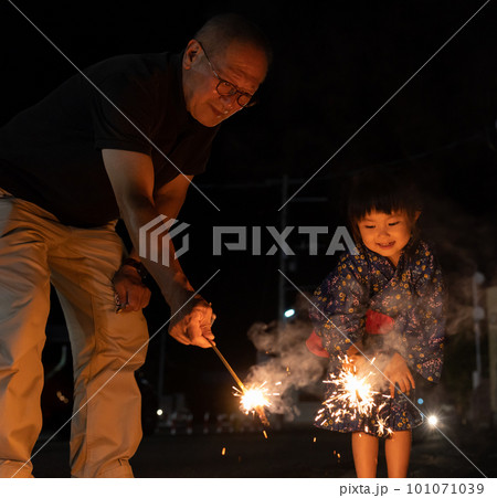 夏休みに帰省しておじいちゃんと花火をする子供 101071039