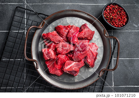 Pieces of raw diced beef fillet meat. Black background. Top view Pieces of raw diced beef fillet meat. Black background. Top view 101071210