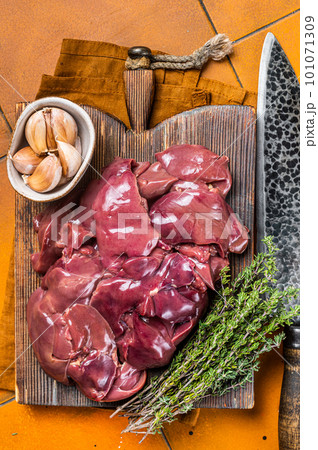 Raw chicken liver, fresh fowl giblets on wooden board. Orange background. Top view Raw chicken liver, fresh fowl giblets on wooden board. Orange background. Top view 101071309