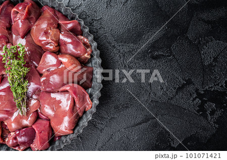 Uncooked Raw chicken liver, poultry offals in steel plate. Black background. Top view. Copy space Uncooked Raw chicken liver, poultry offals in steel plate. Black background. Top view. Copy space 101071421