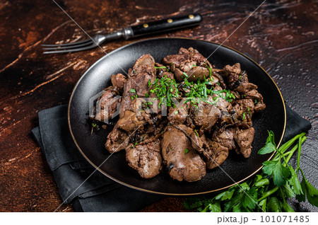 Fried chicken liver with onions and parsley in a plate. Dark background. Top view Fried chicken liver with onions and parsley in a plate. Dark background. Top view 101071485