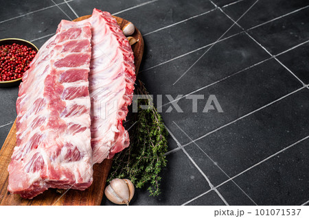 Fresh Pork Spareribs, Raw spare loin ribs on a wooden board with thyme and spices. Black background. Top view. Copy space 101071537