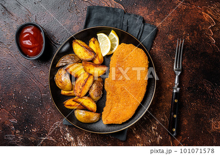 Roast pork schnitzel with fried potato, cooked meat steak. Dark background. Top view Roast pork schnitzel with fried potato, cooked meat steak. Dark background. Top view 101071578