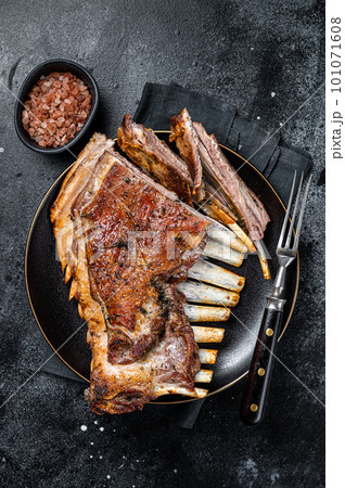 Roasted Rack of lamb ribs, mutton spareribs, sliced meat on plate. Black background. Top view 101071608