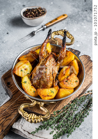 Oven baked quail with potatoes, spices and herbs in a skillet. Gray background. Top view 101071752