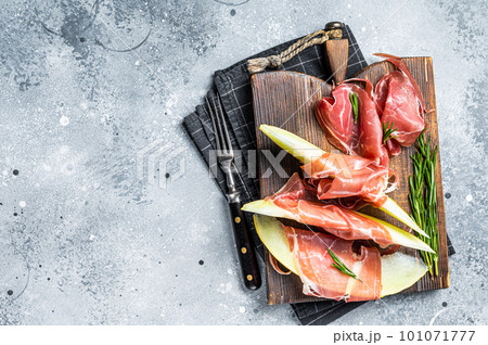 Spanish Tapas Jamon Iberico with goat cheese, melon and honey on a wooden board. Gray background. Top view. Copy space 101071777