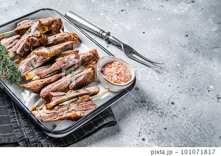 BBQ smoked lamb ribs, mutton spareribs, sliced meat in steel tray with herbs. Gray background. Top view. Copy space BBQ smoked lamb ribs, mutton spareribs, sliced meat in steel tray with herbs. Gray background. Top view. Copy space 101071817