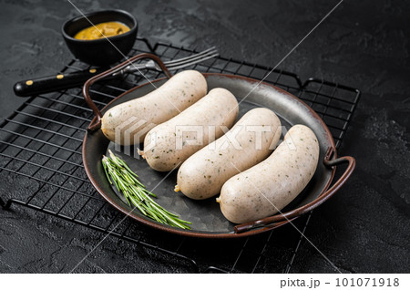 Traditional German Bavarian white sausage in steel tray with mustard. Black background. Top view Traditional German Bavarian white sausage in steel tray with mustard. Black background. Top view 101071918