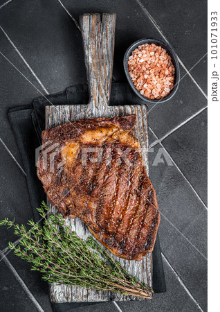 Barbecue aged wagyu Rib Eye beef meat steak with thyme on wooden board. Black background. Top view 101071933