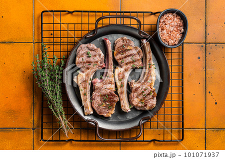 BBQ with Grilled lamb meat chops, mutton steaks with herbs. Orange background. Top view 101071937