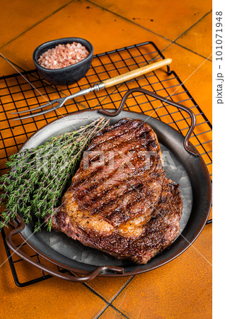 BBQ Grilled wagyu Rib Eye beef meat steak with herbs in steel tray. Orange background. Top view 101071948