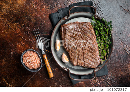 Grilled flank beef steak with herbs. Dark background. Top view 101072217