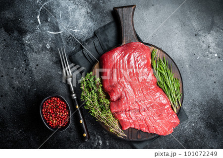 Raw flank beef steak, uncooked meat with herbs. Black background. Top view Raw flank beef steak, uncooked meat with herbs. Black background. Top view 101072249