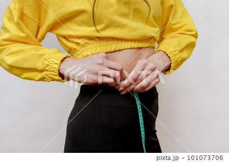 Close up shot of woman with slim body measuring her waistline Close up shot of woman with slim body measuring her waistline 101073706
