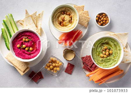assorted hummus dips in bowls, served with fresh vegetables and crackers. assorted hummus dips in bowls, served with fresh vegetables and crackers. 101073933