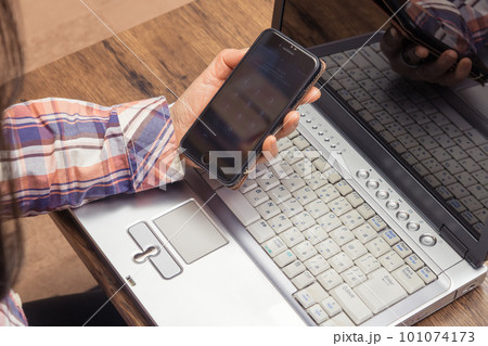 【ノートパソコンとスマホを操作する女性の手元】 101074173