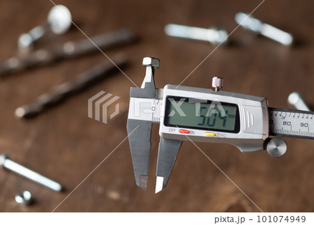 Modern electronic caliper on blurred wooden background 101074949