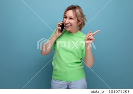 horizontal photo of a cheerful joyful adorable blond woman with a smartphone in her hands on a blue horizontal photo of a cheerful joyful adorable blond woman with a smartphone in her hands on a blue 101075203