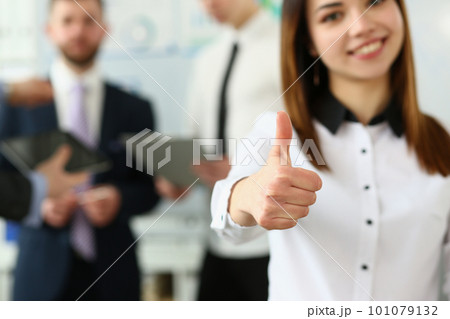 Businessman holds thumbs up in background are business partners Businessman holds thumbs up in background are business partners 101079132