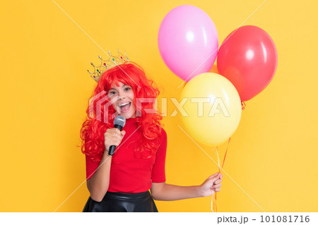child smile in crown with microphone and party balloon on yellow background child smile in crown with microphone and party balloon on yellow background 101081716