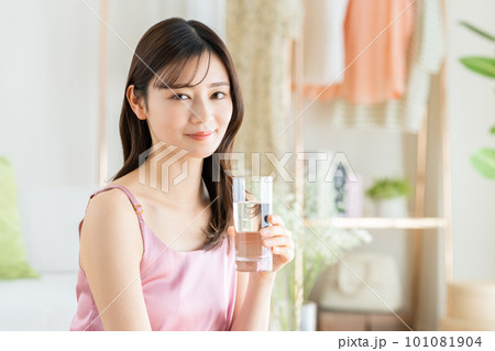 リビングでミネラルウォーターを飲む若い女性 リビングでミネラルウォーターを飲む若い女性 101081904