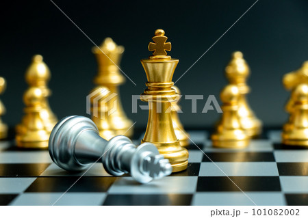Gold king chess piece win over lying down silver king with other gold chess piece stand behind on black background 101082002