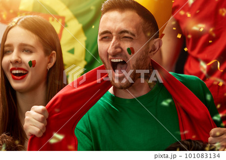 Excited and emotional people, portugal football fans emotionally cheering up favourite team during match at stadium Excited and emotional people, portugal football fans emotionally cheering up favourite team during match at stadium 101083134