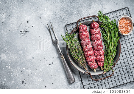 Raw Turkish Urfa kebab decorated with herbs, spices and meat fork. Gray background. Top view. Copy space 101083354