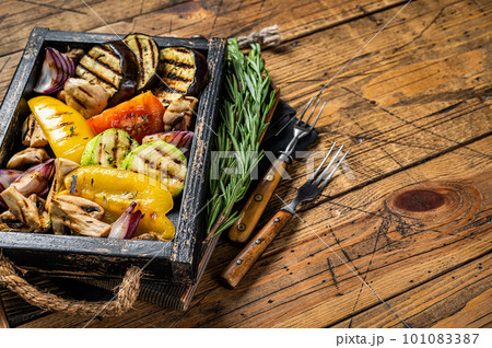 Assortment of grilled Vegetables in a wooden box, bell pepper, zucchini, eggplant, onion and tomato. Wooden background. Top view. Copy space 101083387