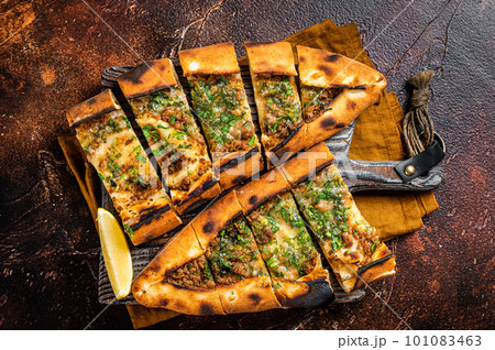Traditional Turkish baked pide, Middle Eastern snack. Turkish pizza. Dark background. Top view Traditional Turkish baked pide, Middle Eastern snack. Turkish pizza. Dark background. Top view 101083463
