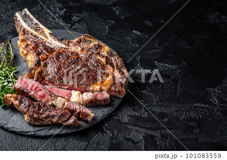 Roasted Tomahawk or cowboy with bone beef meat steak. Black background. Top view. Copy space Roasted Tomahawk or cowboy with bone beef meat steak. Black background. Top view. Copy space 101083559
