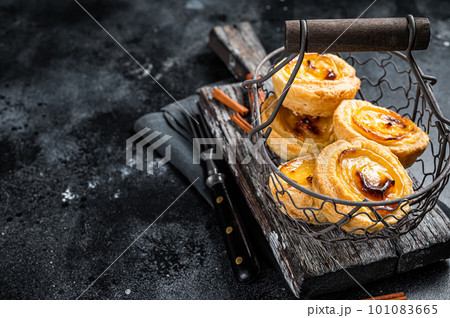 Traditional Lisbon Pasteis de nata in a basket. Black background. Top view. Copy space 101083665