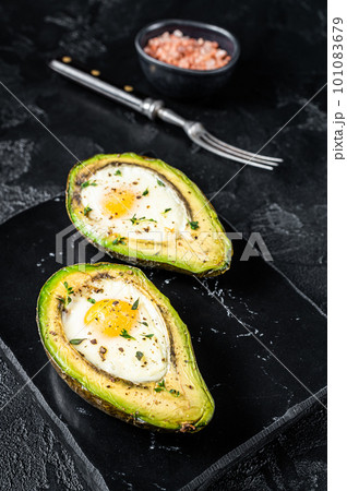 Eggs baked in avocado with herbs and spices. Black background. Top view 101083679