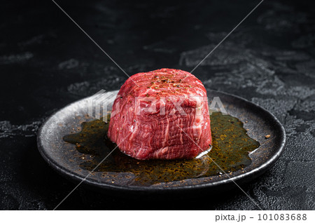 Fillet Mignon prime beef steak, raw dry aged marble meat with herbs and spices ready for cooking. Black background. Top view 101083688