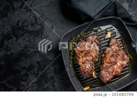 Grilled Pork steaks, neck meat on grill pan. Black background. Top view. Copy space Grilled Pork steaks, neck meat on grill pan. Black background. Top view. Copy space 101083709