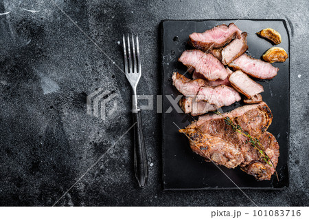 Grilled sliced pork loin steak on marble board. Black background. Top view. Copy space Grilled sliced pork loin steak on marble board. Black background. Top view. Copy space 101083716