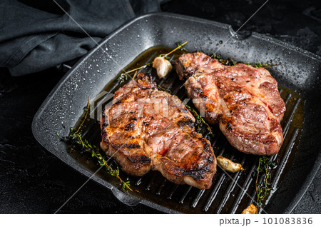 Grilled Pork steaks, neck meat on grill pan. Black background. Top view Grilled Pork steaks, neck meat on grill pan. Black background. Top view 101083836