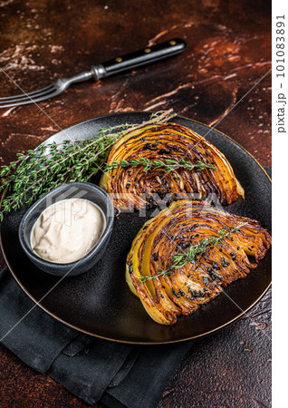 Vegan grilled cabbage steaks with sauce on a black plate. Dark background. Top view Vegan grilled cabbage steaks with sauce on a black plate. Dark background. Top view 101083891