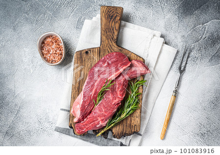 Butcher choise Bavette raw beef meat steak or flank flap on a wooden board with herbs. White background. Top view 101083916
