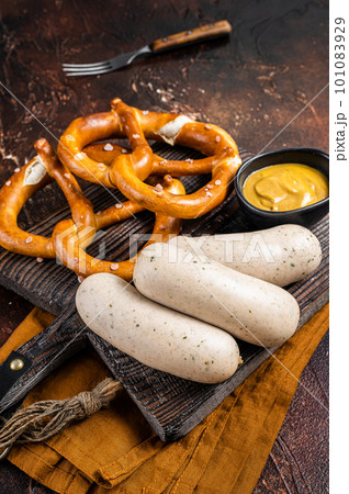 Traditional German pretzel with white sausage and mustard. Dark background. Top view Traditional German pretzel with white sausage and mustard. Dark background. Top view 101083929