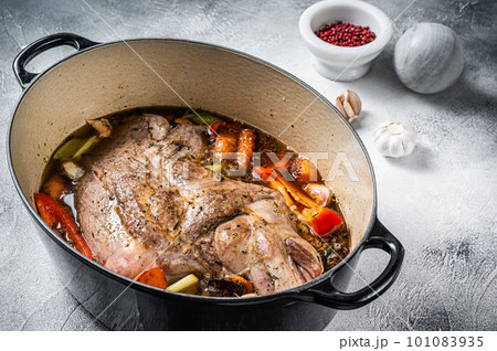 Braised lamb mutton shoulder in a baking dish with vegetables in red wine. White background. Top view Braised lamb mutton shoulder in a baking dish with vegetables in red wine. White background. Top view 101083935