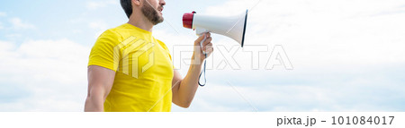 cropped view of man in yellow shirt shout in loudspeaker on sky background 101084017