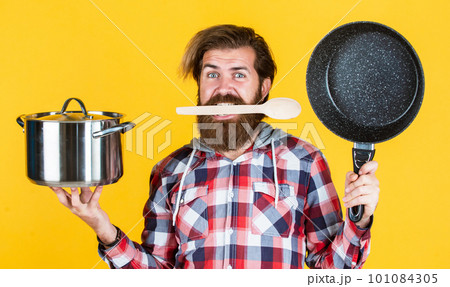 hungry man. Professional chef man cook in checkered shirt. bearded husband. Restaurant. Enameled cast iron cooking vessels. Nonstick pan coated polytetrafluoroethylene teflon. Cooking healthy food 101084305