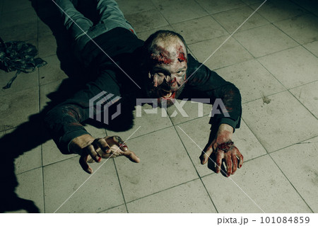 Zombie male creeps on floor halloween concept. Make up skin and blood face Zombie male creeps on floor halloween concept. Make up skin and blood face 101084859