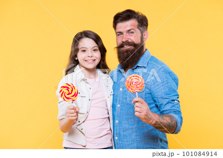 Sweet dessert. Bearded hipster good daddy for adorable daughter. Sweet childhood. Girl child and dad hold colorful lollipops. Sweets and treats concept. Daughter and father eat sweet candies Sweet dessert. Bearded hipster good daddy for adorable daughter. Sweet childhood. Girl child and dad hold colorful lollipops. Sweets and treats concept. Daughter and father eat sweet candies 101084914