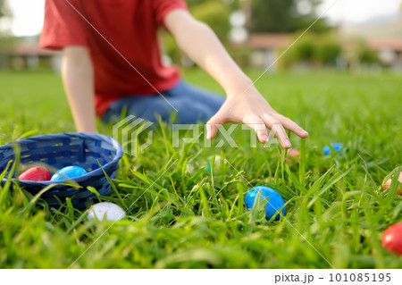 Little boy hunting for eggs in spring garden on Easter day. Traditional festival outdoors. Child celebrate Easter holiday. Focus on hand. 101085195