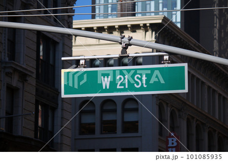 Green big West 21st Street sign hanging on a arch pole in the streets of midtown Manhattan 101085935