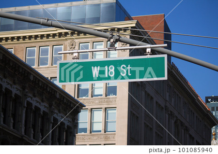 Green big West 18th Street sign hanging on a arch pole in the streets of midtown Manhattan 101085940